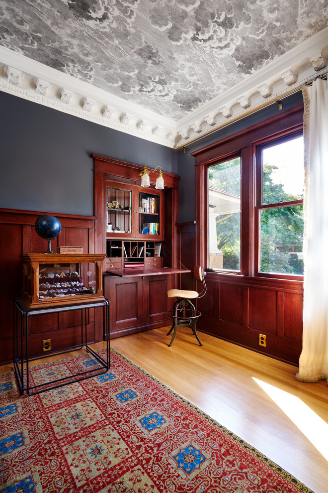 This is an example of a medium sized eclectic home office in Portland with medium hardwood flooring, a built-in desk and black walls.