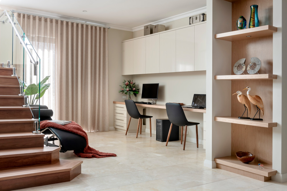 Inspiration för mellanstora moderna hemmabibliotek, med beige väggar, travertin golv, ett inbyggt skrivbord och beiget golv