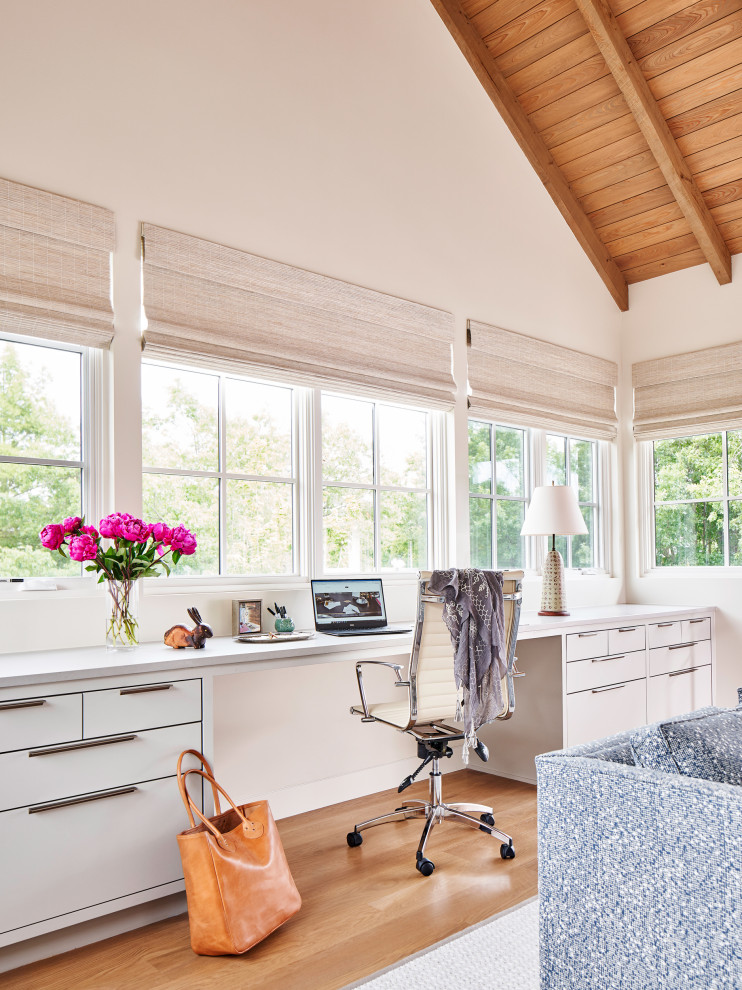 Imagen de despacho abovedado contemporáneo con paredes blancas, suelo de madera en tonos medios, escritorio empotrado, suelo marrón, vigas vistas y madera