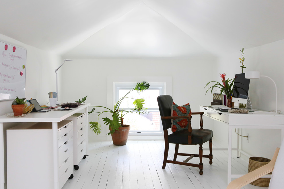 Eklektisches Arbeitszimmer mit Arbeitsplatz, weißer Wandfarbe, gebeiztem Holzboden, freistehendem Schreibtisch und weißem Boden in Raleigh