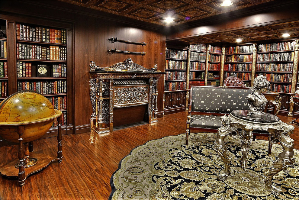 Großes Klassisches Lesezimmer mit brauner Wandfarbe, dunklem Holzboden, Hängekamin, Kaminumrandung aus Backstein, Einbau-Schreibtisch und braunem Boden in Calgary