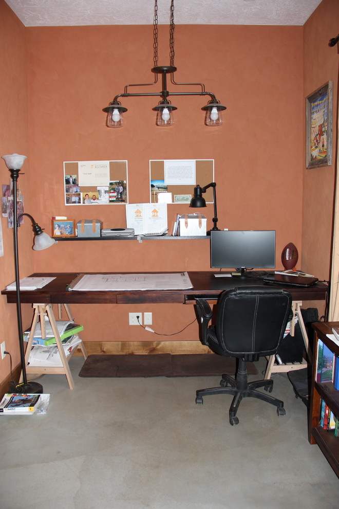 Foto de despacho de estilo de casa de campo de tamaño medio con parades naranjas, suelo de cemento y escritorio independiente