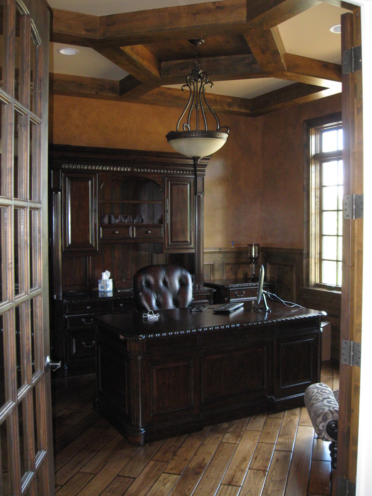 Ejemplo de despacho clásico de tamaño medio con suelo de madera oscura, escritorio independiente y paredes marrones