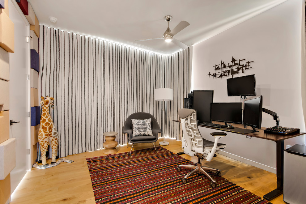 Imagen de despacho actual de tamaño medio sin chimenea con paredes blancas, suelo de madera clara, escritorio independiente y suelo beige