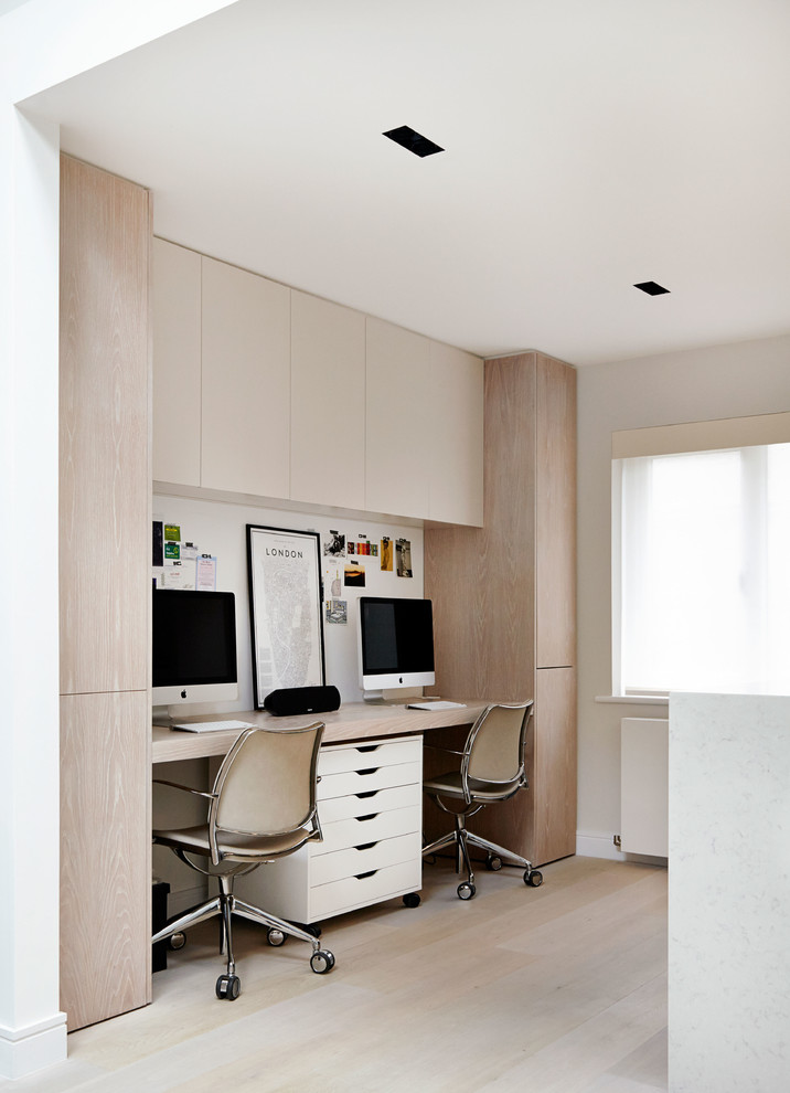 Photo of a contemporary home office in London with white walls, light hardwood flooring and a built-in desk.
