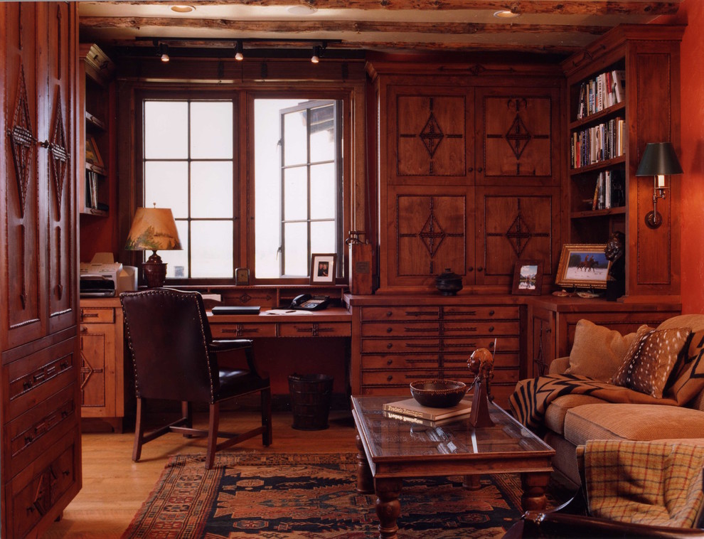Exemple d'un grand bureau montagne avec un sol en bois brun, un bureau intégré et un mur beige.