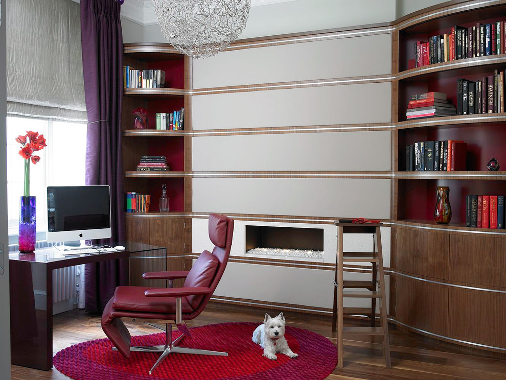 Exempel på ett stort modernt hemmabibliotek, med beige väggar, mellanmörkt trägolv, en bred öppen spis och ett fristående skrivbord