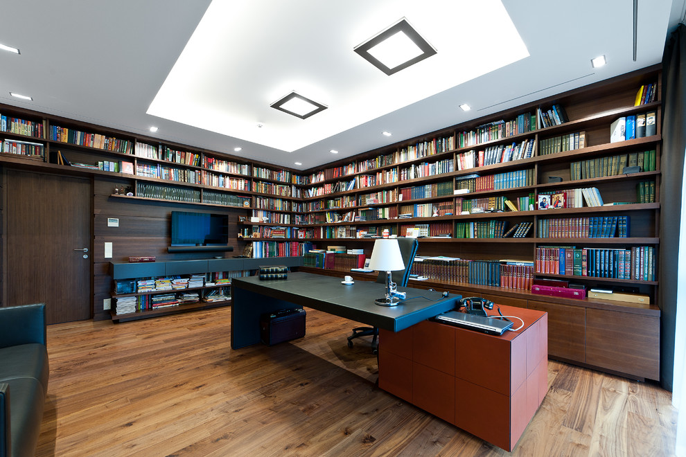 Immagine di uno studio minimal con pavimento in legno massello medio e scrivania autoportante