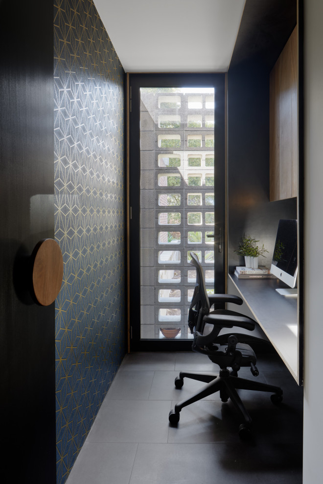 Imagen de despacho minimalista pequeño con paredes azules, suelo de pizarra, escritorio empotrado, suelo gris y papel pintado