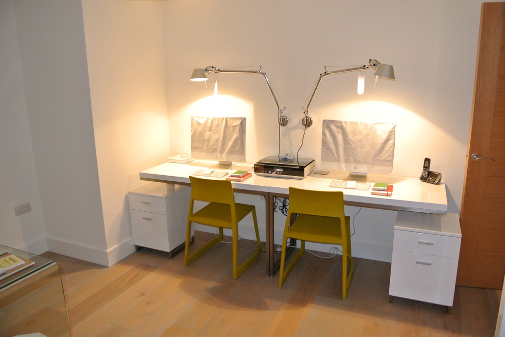 На фото: рабочее место среднего размера в современном стиле с белыми стенами и отдельно стоящим рабочим столом с