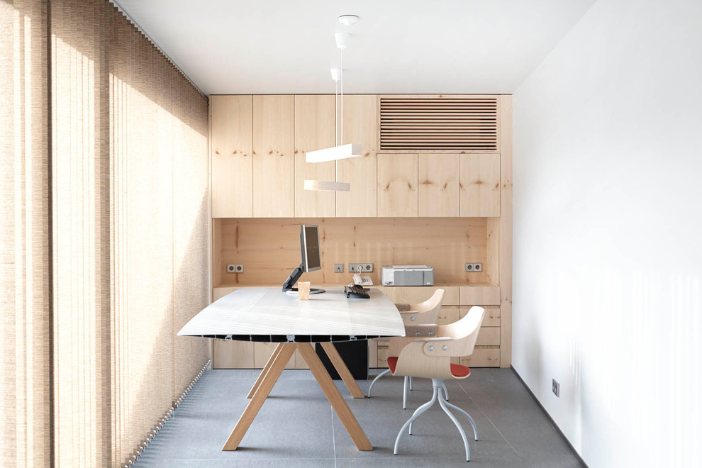 Imagen de despacho actual pequeño sin chimenea con paredes blancas, escritorio independiente y suelo de cemento