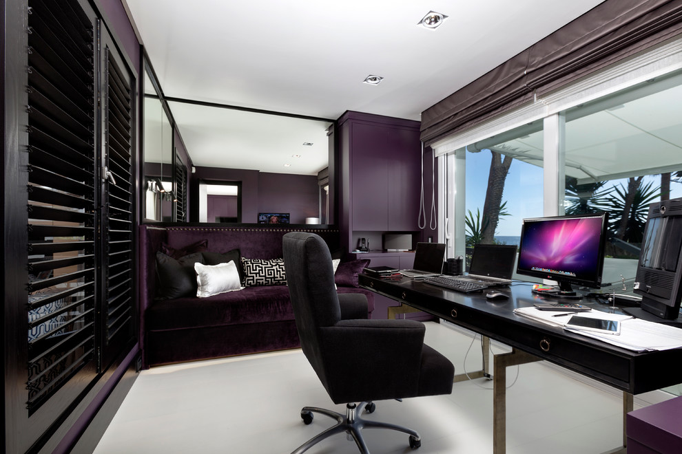 На фото: рабочее место среднего размера в современном стиле с фиолетовыми стенами, ковровым покрытием и отдельно стоящим рабочим столом без камина