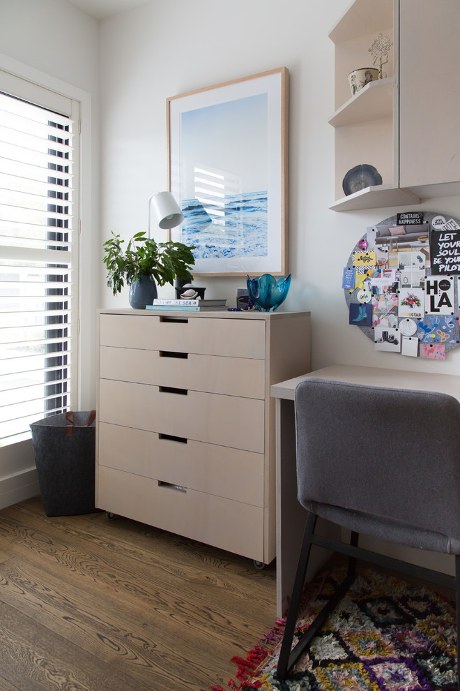 Ejemplo de despacho actual de tamaño medio con paredes blancas, suelo de madera en tonos medios y suelo marrón