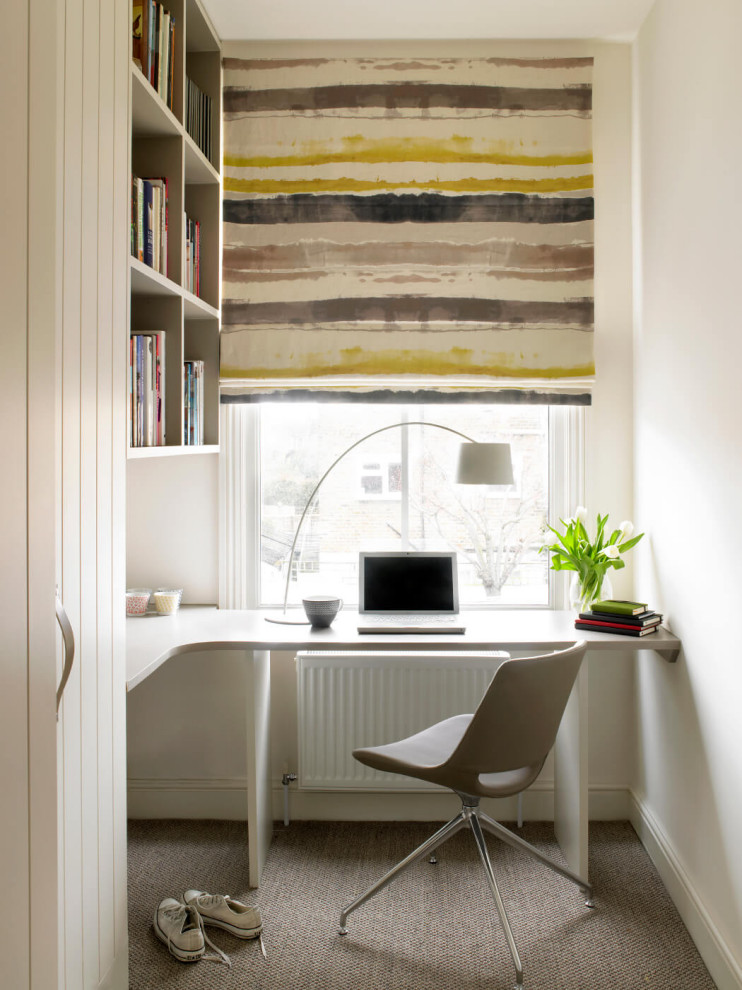 На фото: кабинет в современном стиле с белыми стенами, ковровым покрытием, встроенным рабочим столом и серым полом с