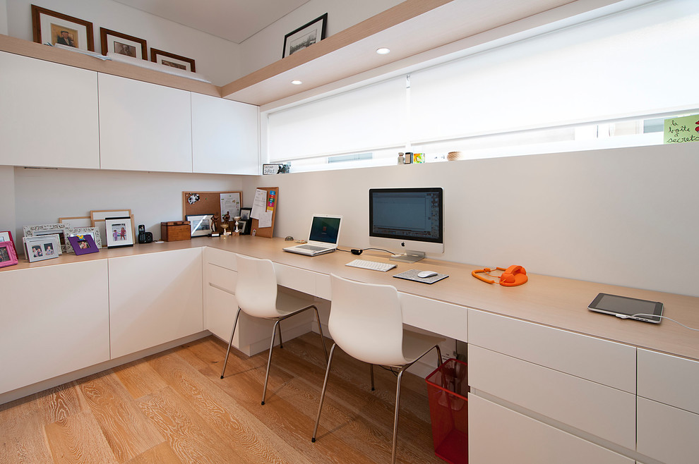 Ejemplo de despacho contemporáneo de tamaño medio sin chimenea con paredes blancas, suelo de madera clara y escritorio empotrado