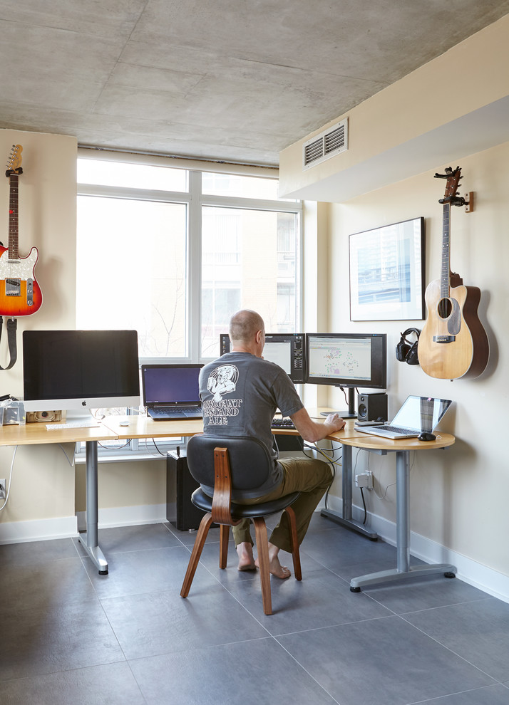 Imagen de despacho moderno de tamaño medio con paredes amarillas, suelo de cemento y escritorio independiente