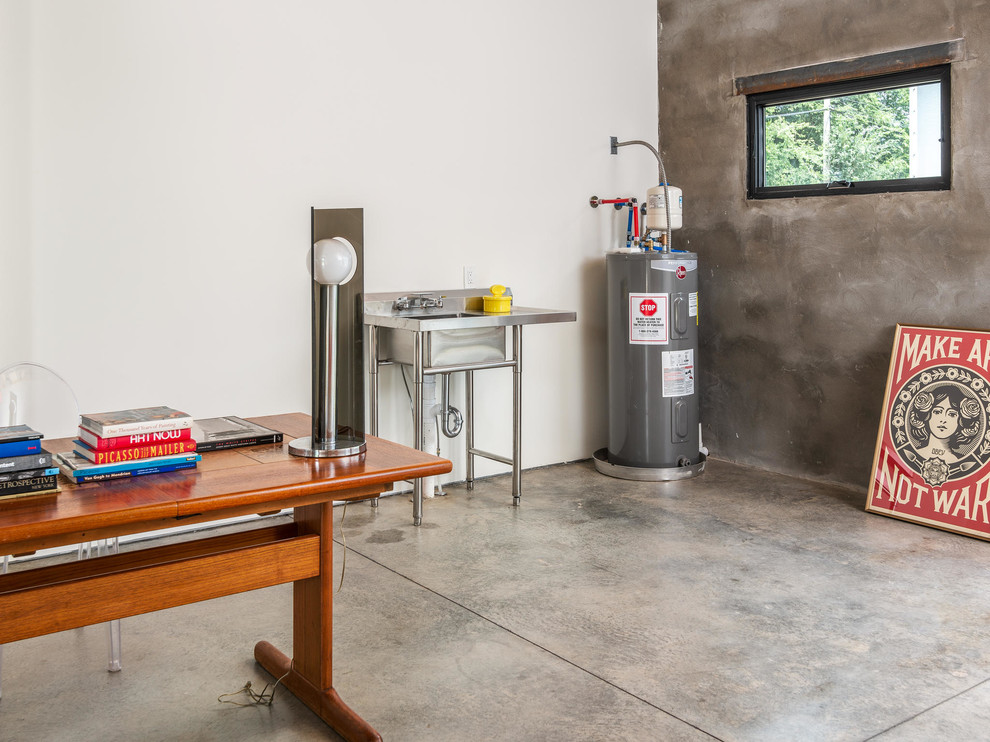 Foto på ett litet industriellt hemmastudio, med vita väggar och betonggolv