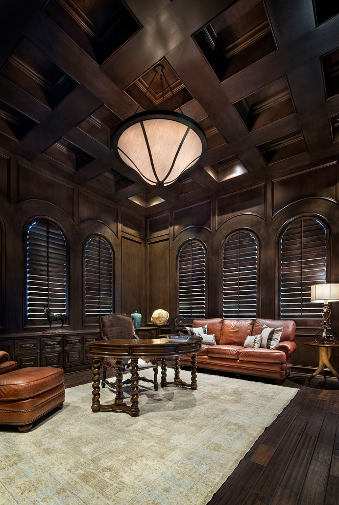Exempel på ett mycket stort medelhavsstil hemmabibliotek, med bruna väggar, mörkt trägolv och ett fristående skrivbord