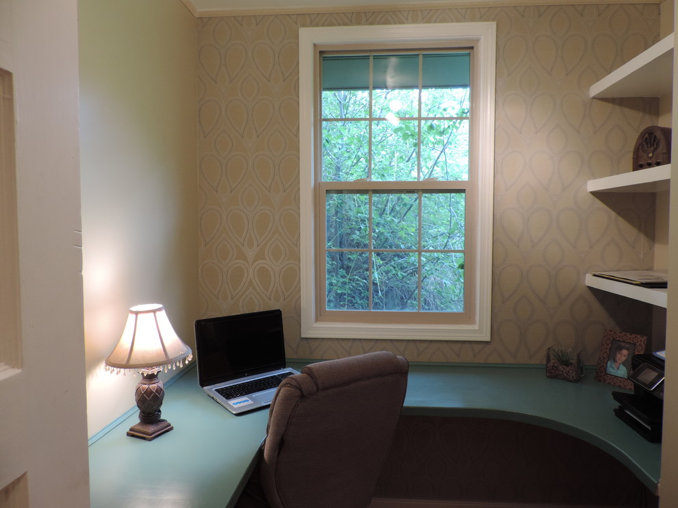 Klassisk inredning av ett litet arbetsrum, med beige väggar, mellanmörkt trägolv och ett inbyggt skrivbord