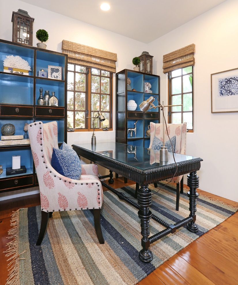 Mediterranes Arbeitszimmer mit weißer Wandfarbe, braunem Holzboden und freistehendem Schreibtisch in Orange County