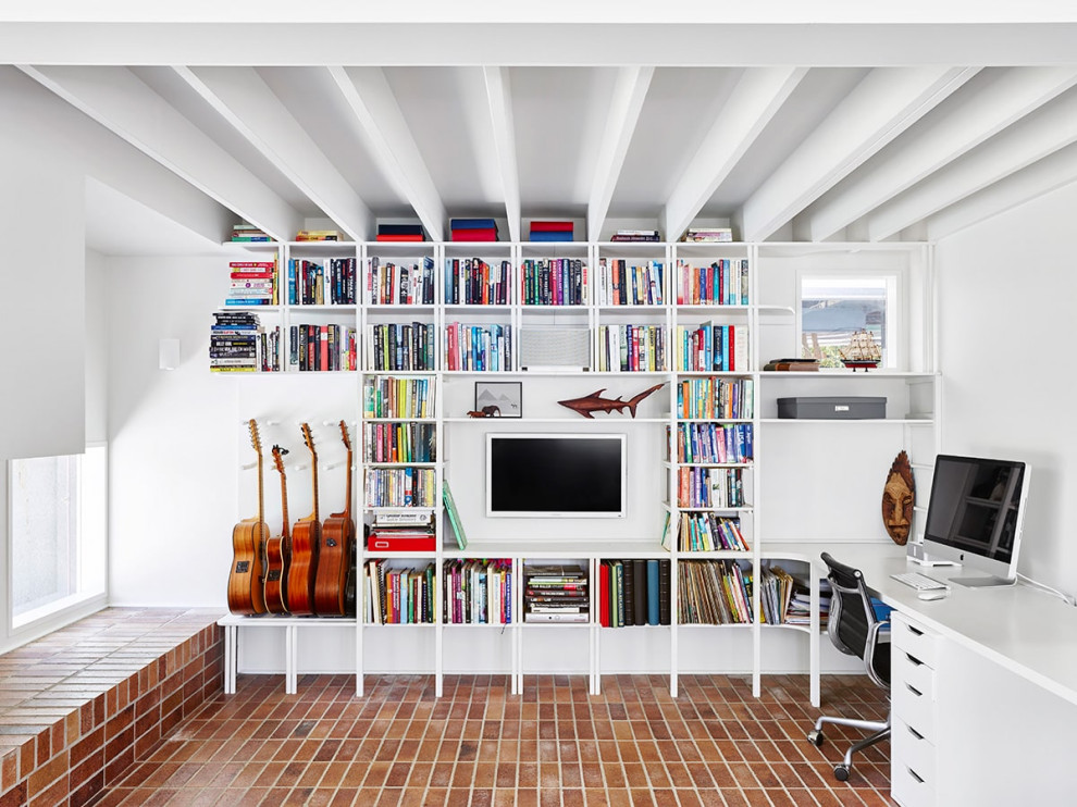 Inredning av ett modernt arbetsrum, med ett bibliotek, vita väggar, tegelgolv, ett inbyggt skrivbord och rött golv