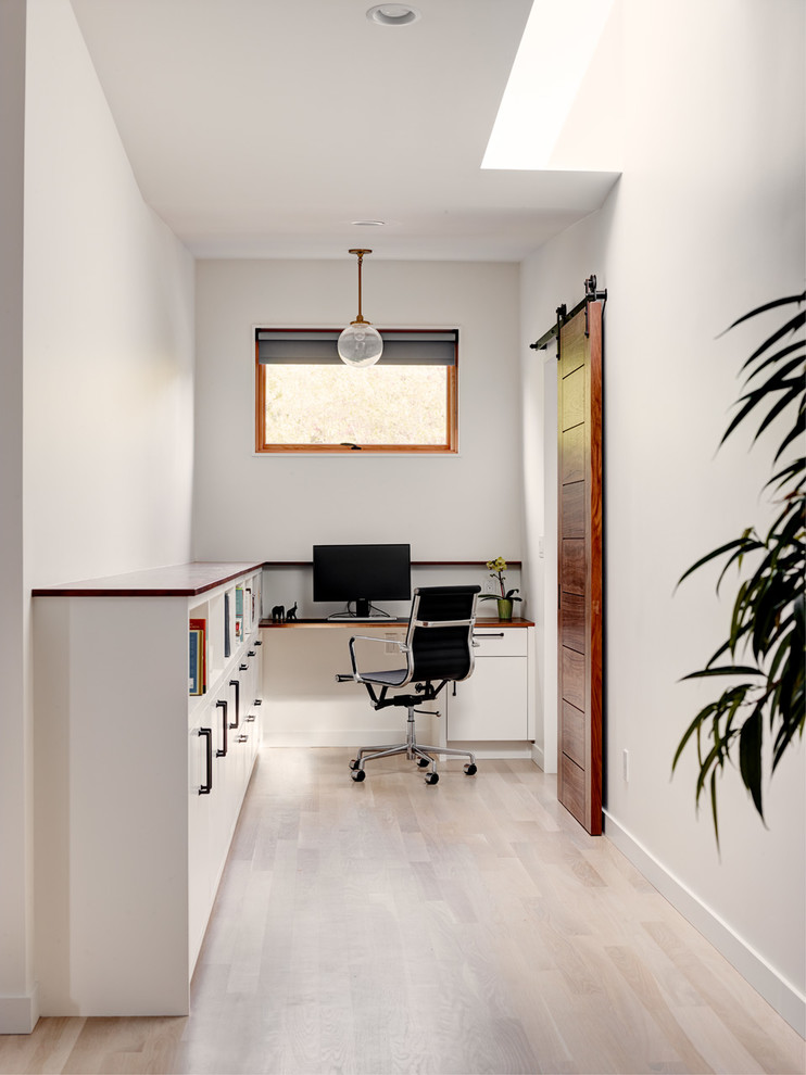 Réalisation d'un bureau design avec un mur blanc, parquet clair, un bureau intégré et un sol beige.