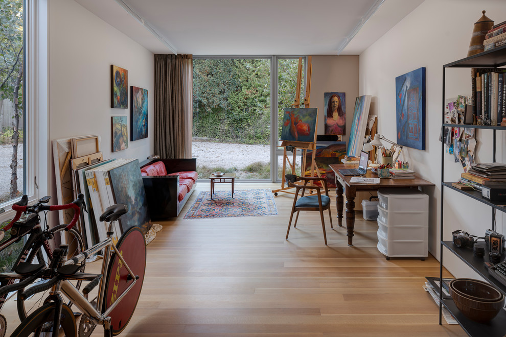 Immagine di un atelier minimal con pareti bianche, pavimento in legno massello medio, scrivania autoportante e pavimento marrone