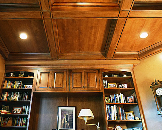 Inredning av ett klassiskt mellanstort hemmabibliotek, med beige väggar, ljust trägolv och ett inbyggt skrivbord