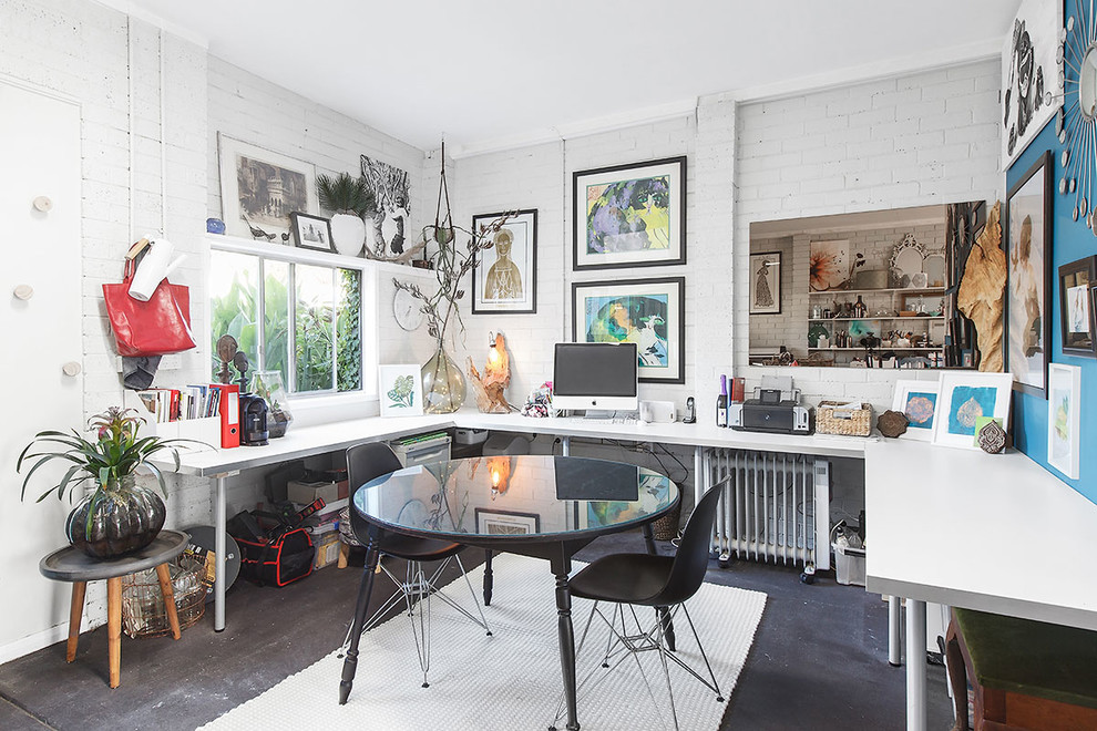 Идея дизайна: домашняя мастерская среднего размера в стиле фьюжн с белыми стенами, бетонным полом, встроенным рабочим столом и черным полом
