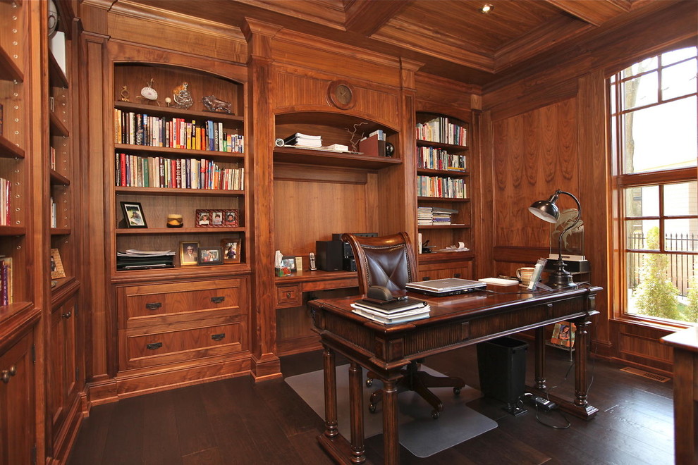 На фото: рабочее место среднего размера в классическом стиле с коричневыми стенами, темным паркетным полом, отдельно стоящим рабочим столом и коричневым полом