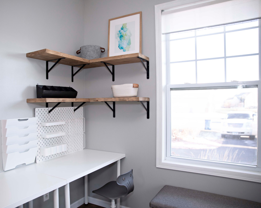 Inspiration for a small contemporary home office in Minneapolis with grey walls, laminate floors, no fireplace, a freestanding desk and brown floors.