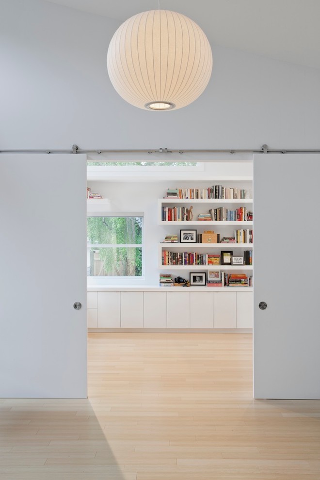 Diseño de despacho moderno con paredes blancas y suelo de madera clara