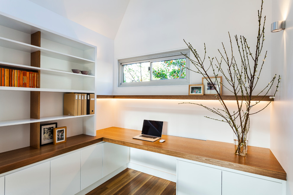 Foto di un piccolo ufficio minimal con pareti bianche, pavimento in legno massello medio e scrivania incassata