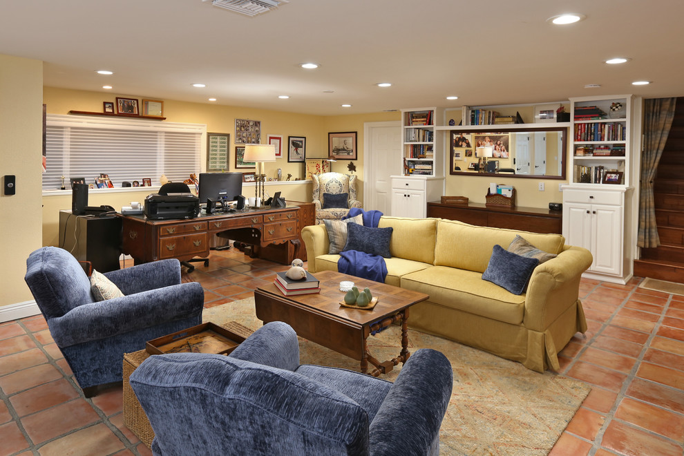 ロサンゼルスにあるお手頃価格の広いトラディショナルスタイルのおしゃれなホームオフィス・書斎 (黄色い壁、テラコッタタイルの床、暖炉なし、自立型机、茶色い床、ライブラリー) の写真