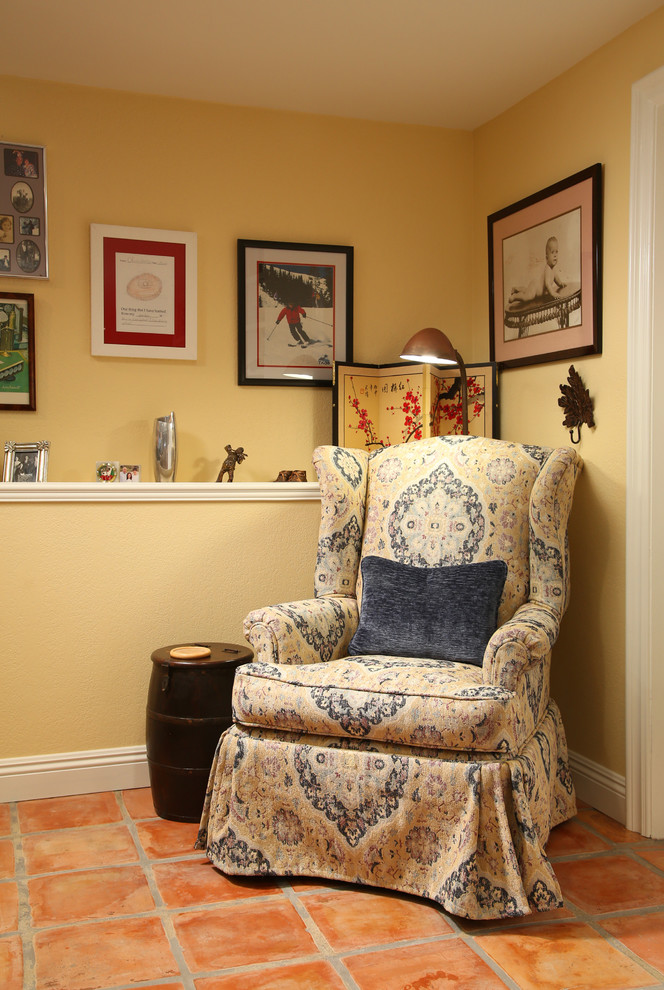Imagen de despacho tradicional grande sin chimenea con paredes amarillas, suelo de baldosas de terracota, escritorio independiente, suelo marrón y biblioteca