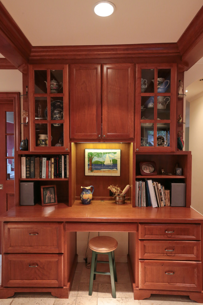This is an example of a small traditional study in San Francisco with beige walls, limestone flooring, a built-in desk and beige floors.