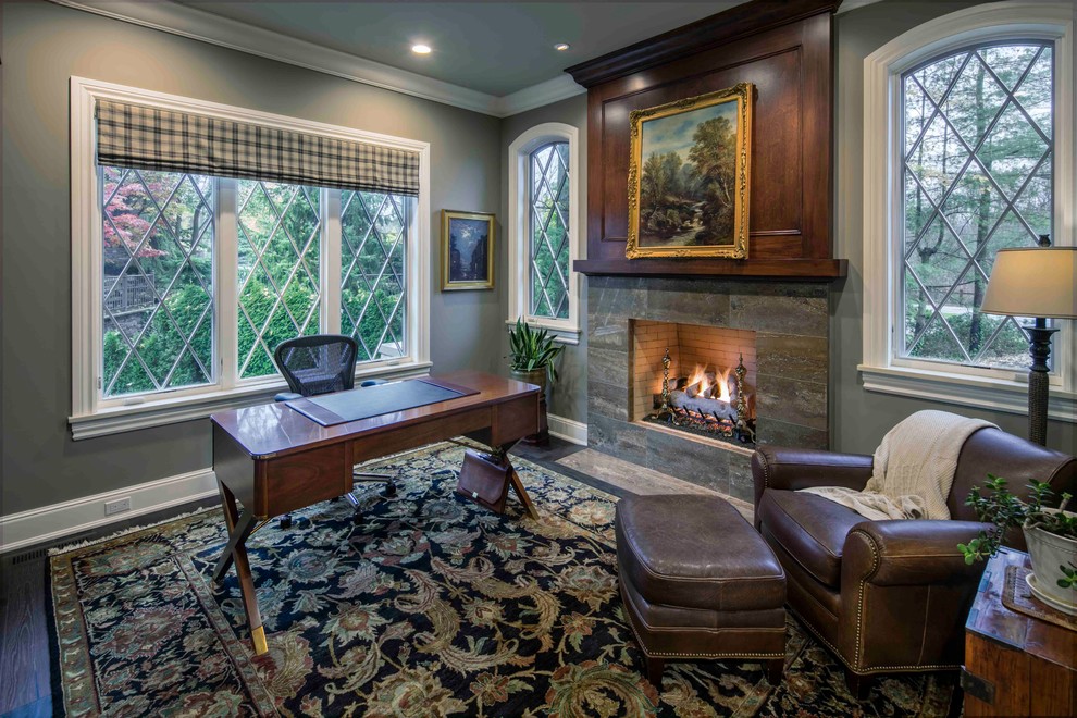Large traditional study in Grand Rapids with grey walls, dark hardwood flooring, a standard fireplace and a freestanding desk.