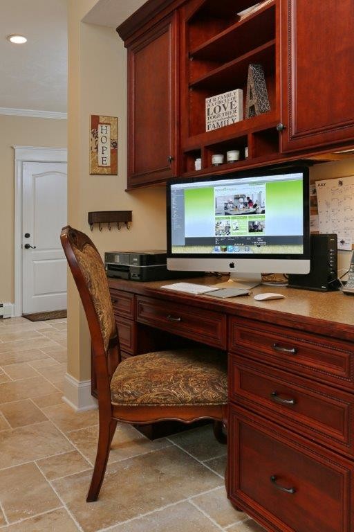 Ejemplo de despacho de estilo americano pequeño sin chimenea con paredes beige, suelo de travertino y escritorio empotrado