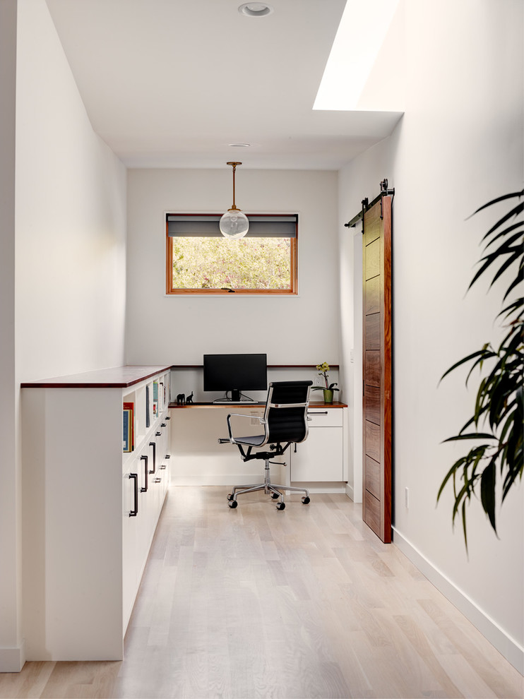 Inredning av ett klassiskt arbetsrum, med vita väggar, ljust trägolv och ett inbyggt skrivbord