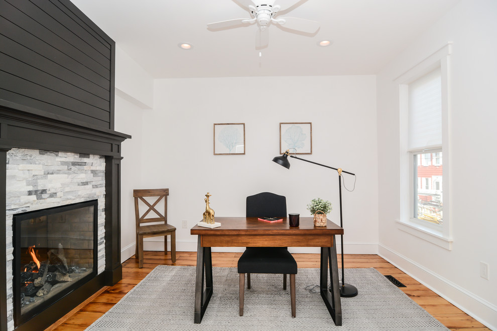 Foto de despacho contemporáneo con paredes blancas, suelo de madera clara, chimenea de doble cara, marco de chimenea de madera, escritorio independiente y suelo marrón