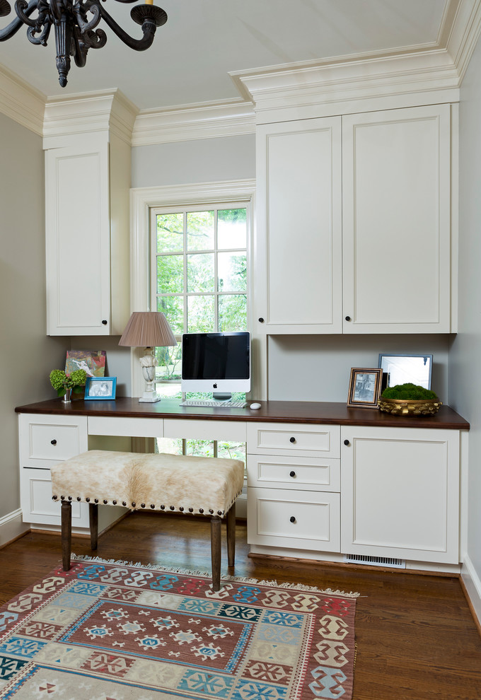 This is an example of a medium sized classic study in Charlotte with beige walls, dark hardwood flooring and a built-in desk.
