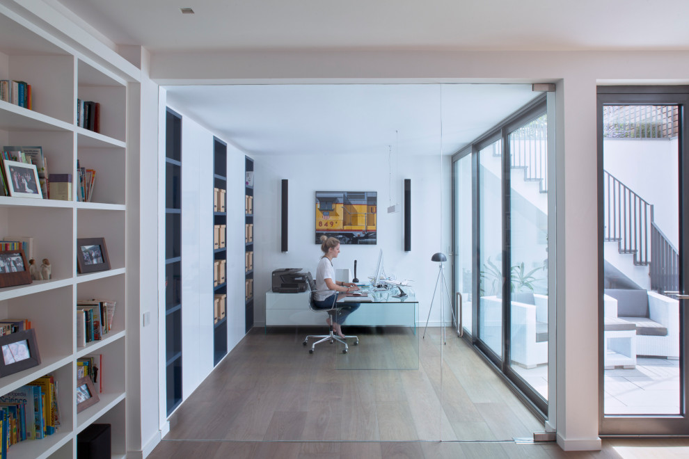 Großes Modernes Arbeitszimmer mit Arbeitsplatz, weißer Wandfarbe, braunem Holzboden, freistehendem Schreibtisch und beigem Boden in London