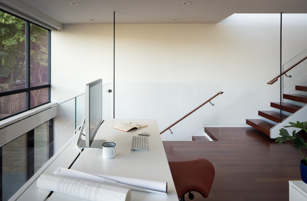 Diseño de despacho minimalista extra grande con paredes blancas, suelo de madera oscura y escritorio empotrado