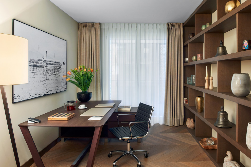 Bild på ett funkis hemmabibliotek, med mellanmörkt trägolv och ett fristående skrivbord