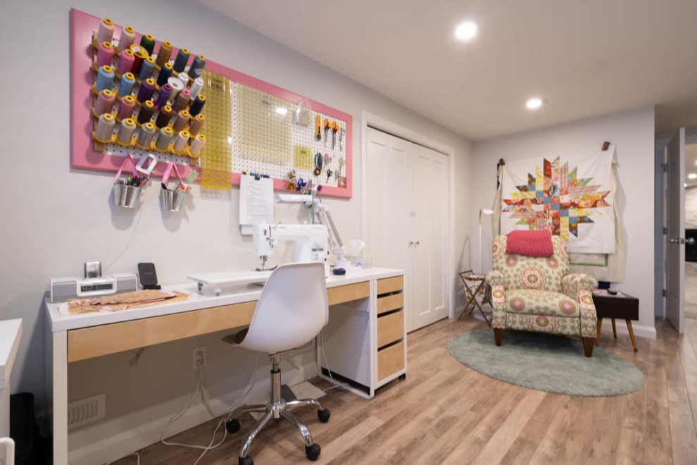 Immagine di una grande stanza da lavoro minimalista con pareti grigie, pavimento in legno massello medio, nessun camino, scrivania autoportante e pavimento marrone