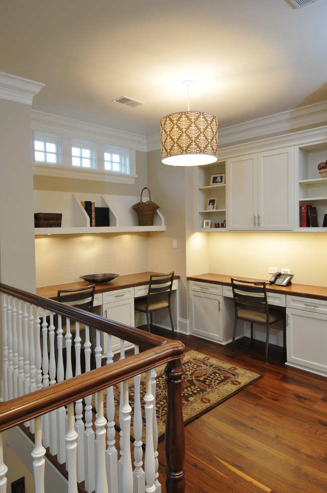 Elegant built-in desk dark wood floor home office photo in Chicago with beige walls
