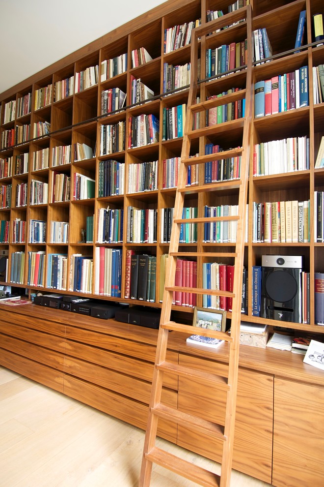 Cette photo montre un grand bureau chic avec une bibliothèque ou un coin lecture, un mur beige, parquet clair, une cheminée ribbon et un manteau de cheminée en plâtre.