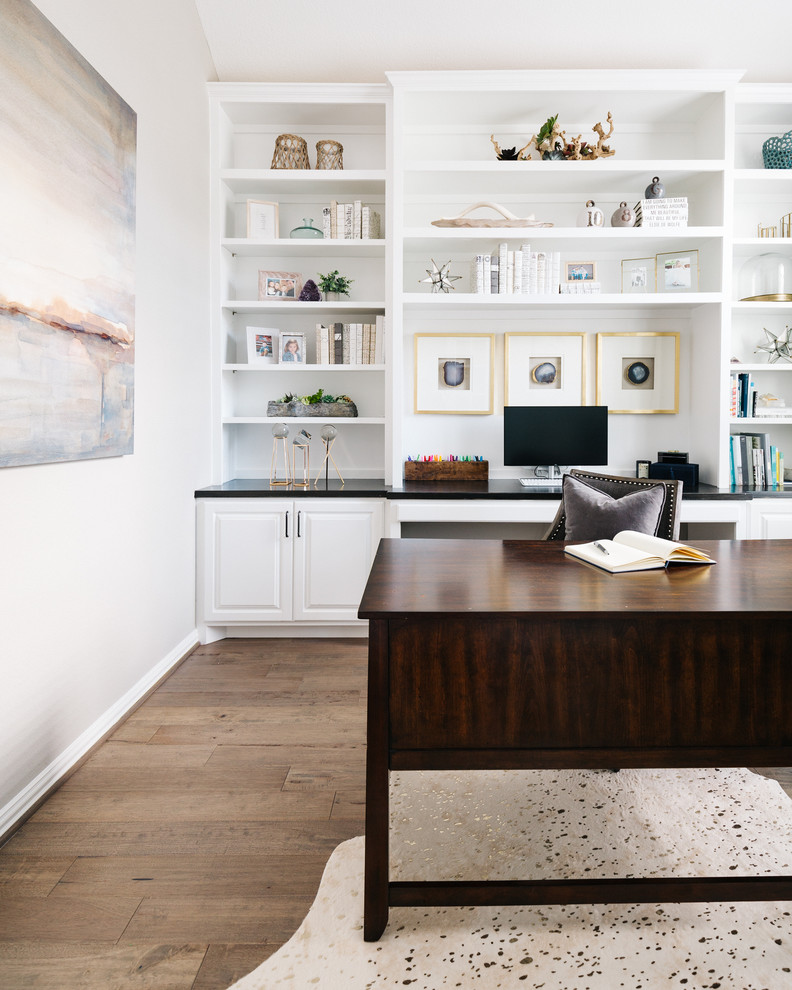 Modelo de despacho tradicional renovado sin chimenea con paredes grises, suelo de madera oscura, escritorio independiente y suelo marrón