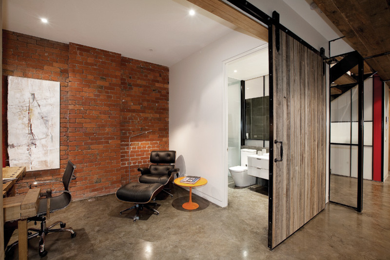 Imagen de despacho industrial con paredes blancas, suelo de cemento y escritorio independiente