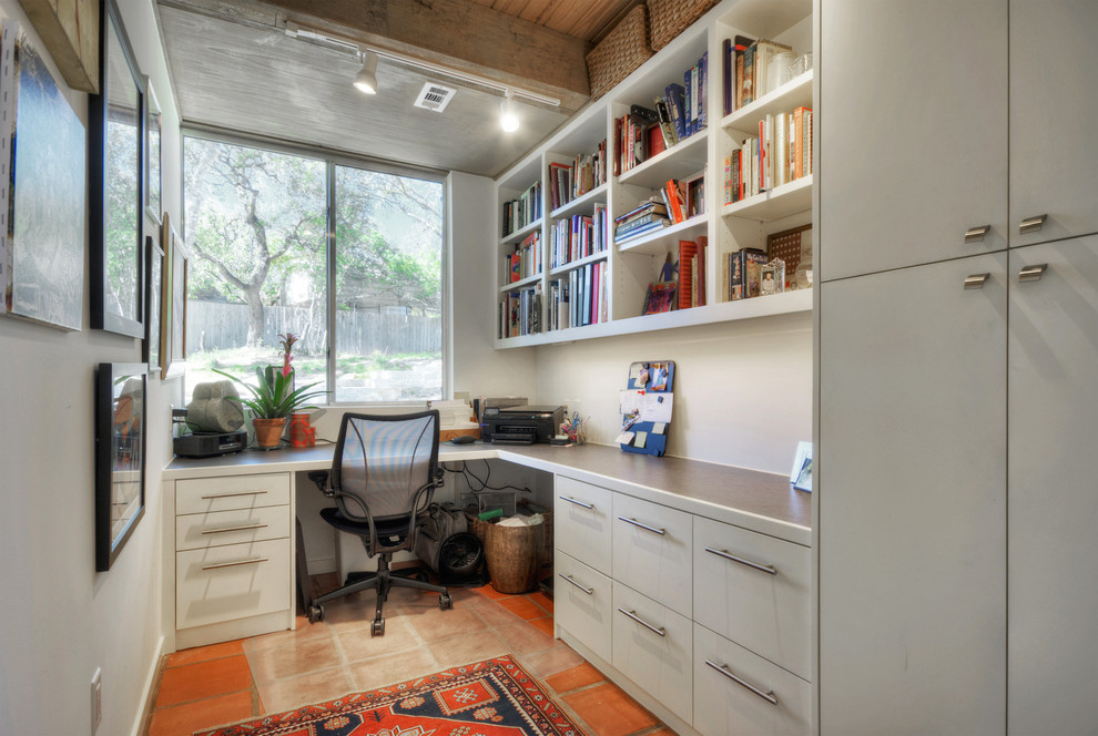 Example of a small trendy built-in desk terra-cotta tile study room design in Denver with white walls and no fireplace